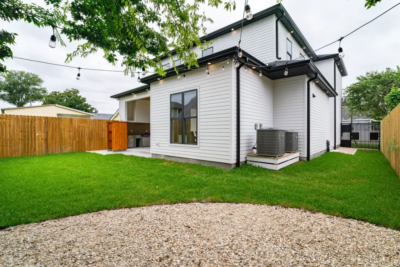 A newly finished weatherboard home with a fresh lawn, gravel area and timber fence